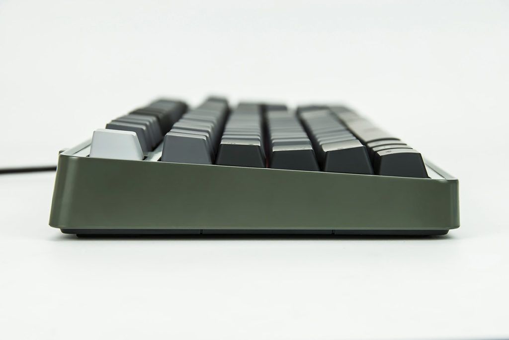 Side view of a keyboard with dark grey keycaps and a green-grey case on a white background